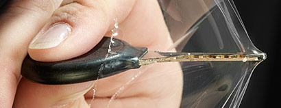 View of a hand pushing a car key into a clear thin sheet of 3M Paint Defender Spray Film