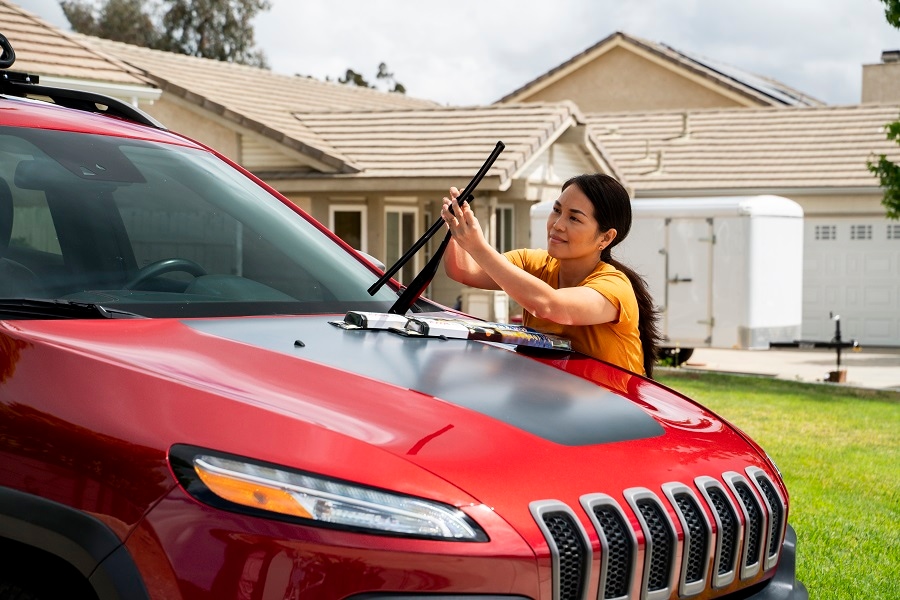 Woman changing the wiper blades on a Jeep.