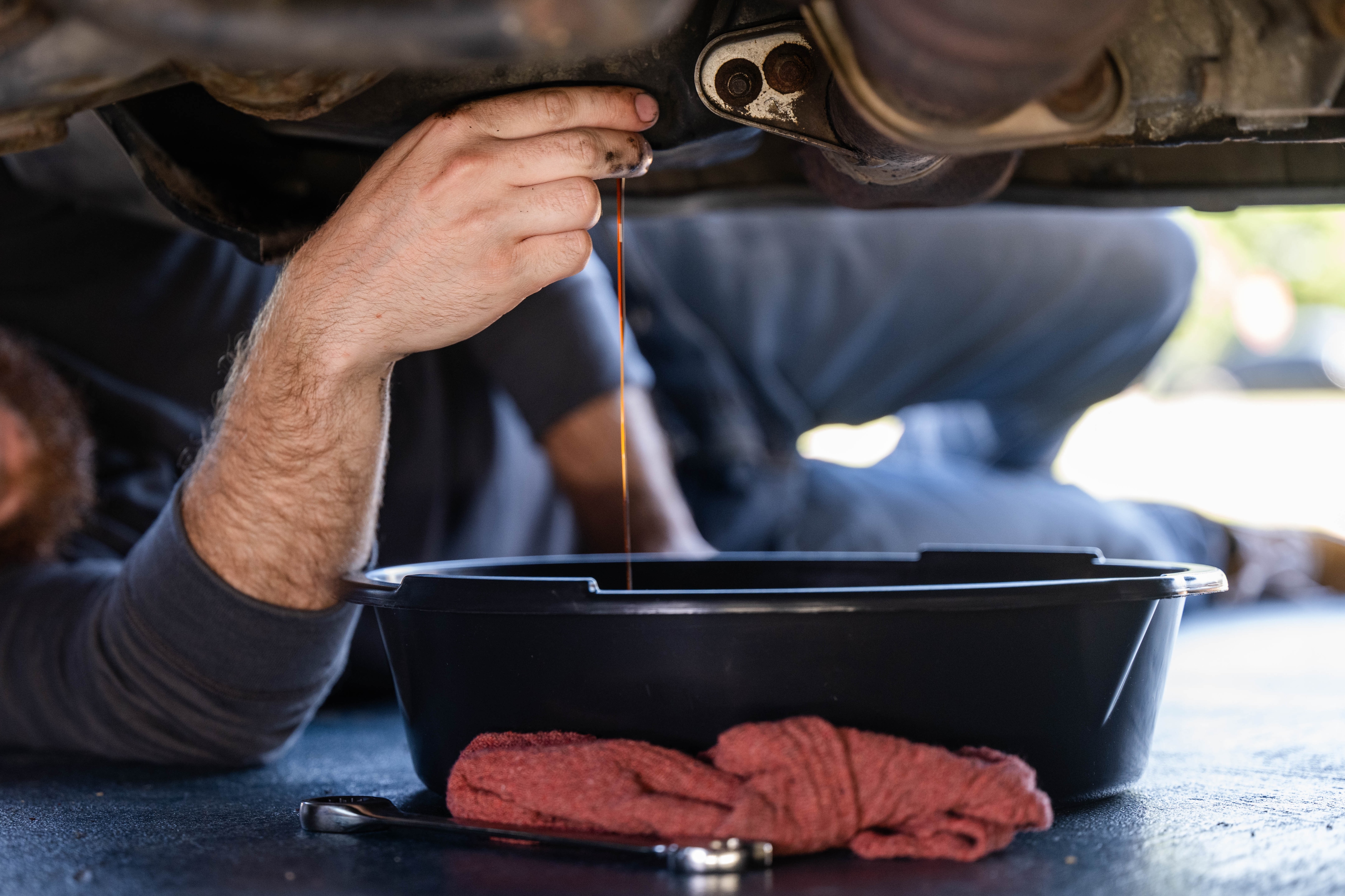 Man under vehicle draining oil