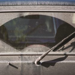 A rear windshield wiper with dust all over the rear window except where the wiper sweeps.