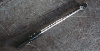 A torque wrench sitting on top of scratched concrete flooring.