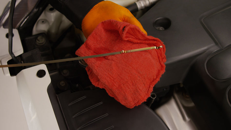 person showing how to check oil with a dipstick