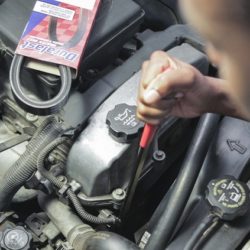 A person using a serpentine belt tool to loosen and remove the old belt before installing a new one.