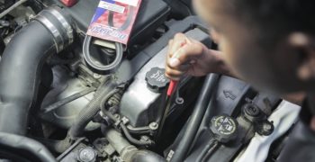 A person using a serpentine belt tool to loosen and remove the old belt before installing a new one.