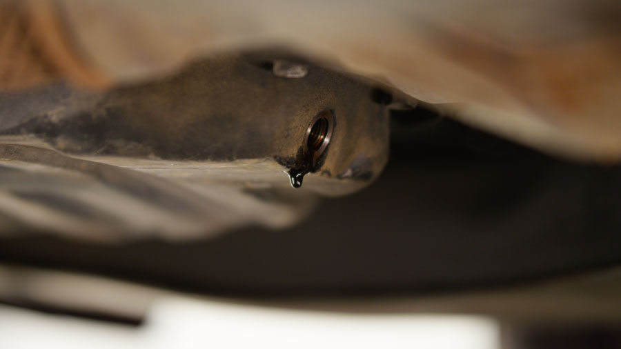 oil pan with no oil pan nut installed and a drip of oil