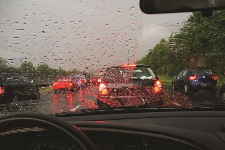 A driver's seat view of cars driving on the freeway in the rain.