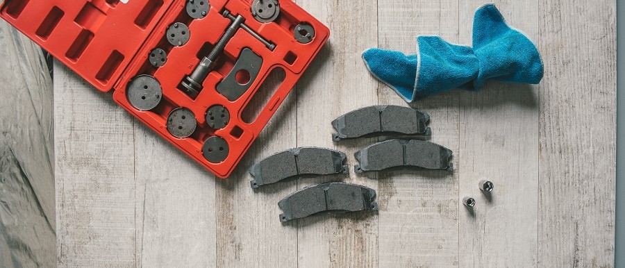 Brake pads and a brake tool sitting on a wood floor, waiting to be installed.
