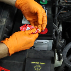 hands wearing orange gloves applying washers and dielectric grease