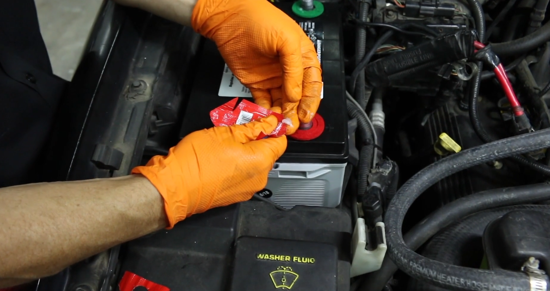 hands wearing orange gloves applying washers and dielectric grease