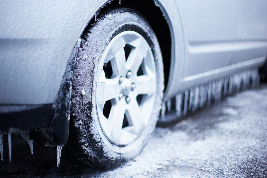 White car with wheels on icy road