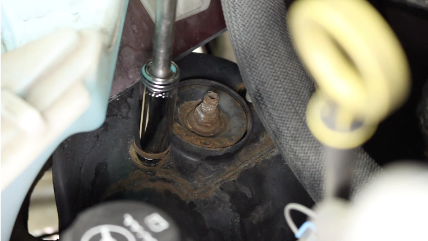 Person using a ratchet to remove the bolts which attach the shock assembly to the vehicle frame