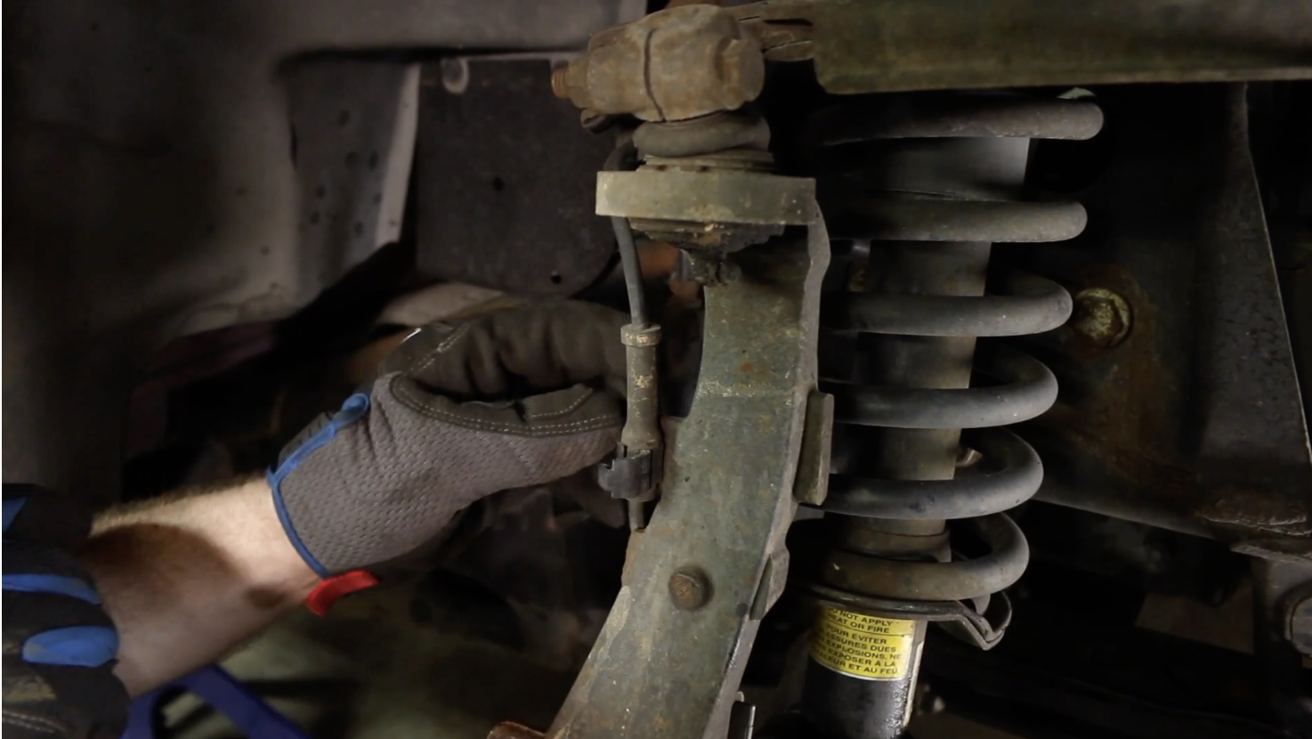 Person disconnecting the wheel speed sensor on a Chevy Trailblazer
