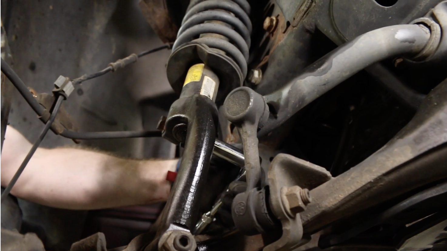Person removing the top bolt from the strut mounting bracket