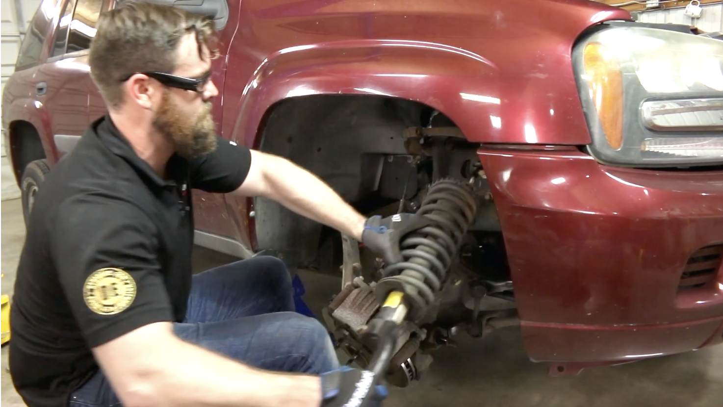 Technician removing strut assembly from the front drivers side of a Chevy Trailblazer