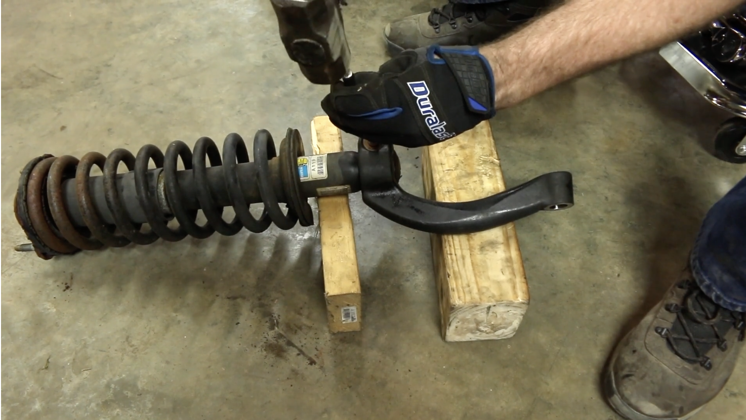 person knocking the knock out bolt from the strut assembly
