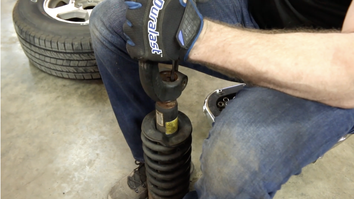 Person separating the mounting bracket from the strut assembly from a Chevy Trailblazer