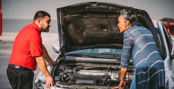 AutoZoner and customer talking while standing over the open engine bay of a compact sedan