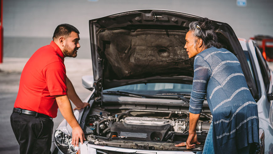 AutoZoner and customer talking while standing over the open engine bay of a compact sedan