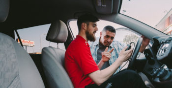 AutoZone associate looking at a code reader plugged into a customer's vehicle while explaining how to fix P0011