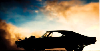 Forced induction muscle car resting on the road in the light of the setting sun. A wastegate peaks out from the top of the hood to allow compressed air to escape from this supercharged or turbocharged ride.
