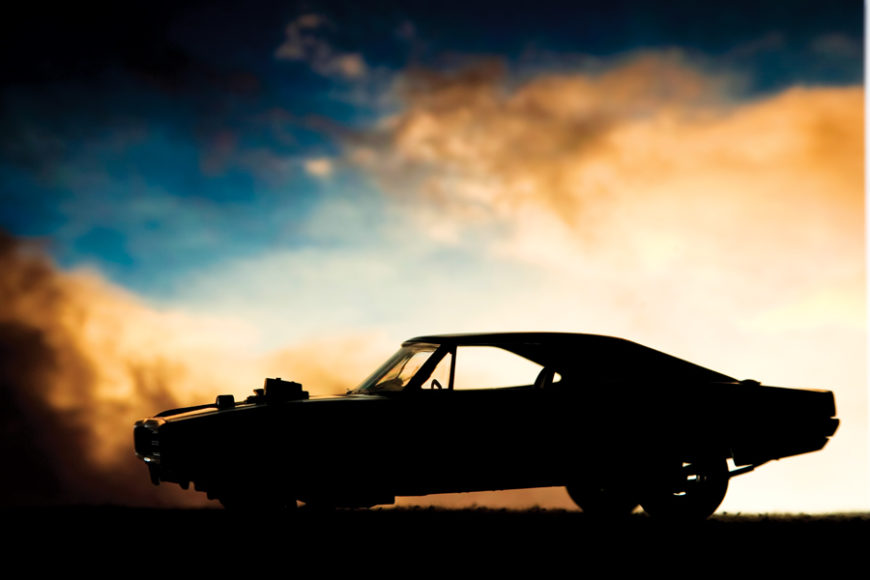 Forced induction muscle car resting on the road in the light of the setting sun. A wastegate peaks out from the top of the hood to allow compressed air to escape from this supercharged or turbocharged ride.