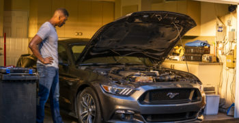 Man looking at his Mustang in the garage and wondering 