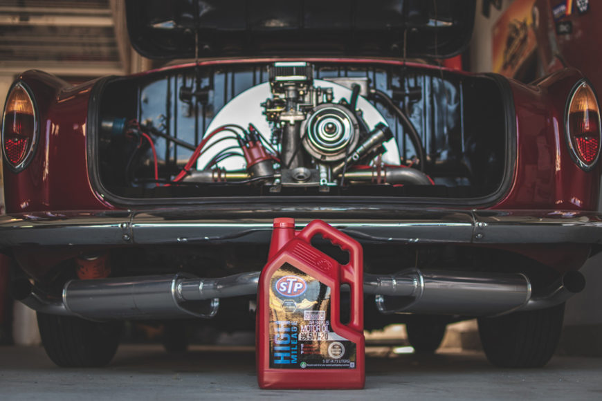 STP motor oil in front of a red classic car in the garage