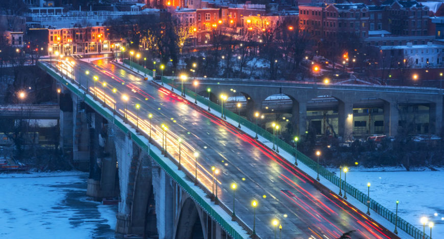 Many cars driving during at Christmas-time along a bridge
