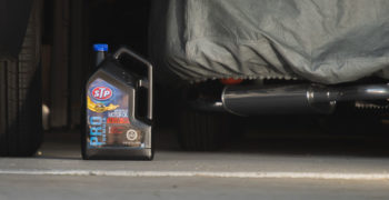Jug of motor oil sitting between two cars in the garage
