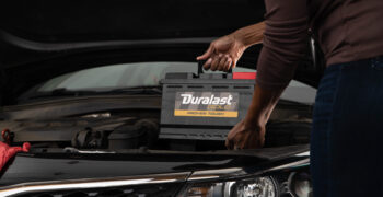 Duralast gold battery being installed in car by a woman
