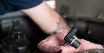 mechanic installing sensor under hood of vehicle 7