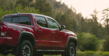 red truck driving through wooded country side at sunset