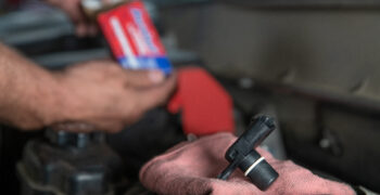 mechanic installing sensor under hood of vehicle 1